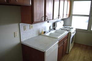 Kitchen with white appliances, light countertops, decorative backsplash, dark wood-style floors, and dark wood finish cabinets