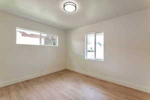 Spare room with a textured ceiling and light wood-style floors