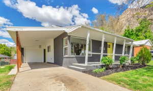 View of front facade with driveway, a carport, and a front yard