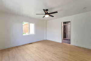 Unfurnished bedroom with light wood-style floors, ceiling fan, and connected bathroom