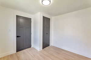 Unfurnished bedroom with light wood-style floors, a closet, and a textured ceiling