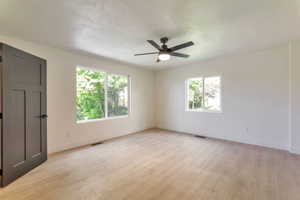 Unfurnished room featuring plenty of natural light, light wood-type flooring, a textured ceiling, and a ceiling fan