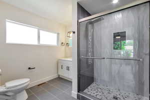 Full bathroom featuring a stall shower, vanity, and dark tile patterned floors