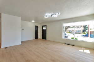 Spare room with a textured ceiling and light wood-style flooring