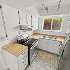 Kitchen with white cabinetry, stainless steel appliances, light countertops, track lighting, and a raised ceiling
