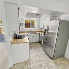 Kitchen featuring light countertops, stainless steel appliances, white cabinetry, extractor fan, and a raised ceiling