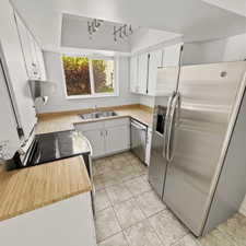 Kitchen with light countertops, stainless steel appliances, white cabinets, a tray ceiling, and rail lighting