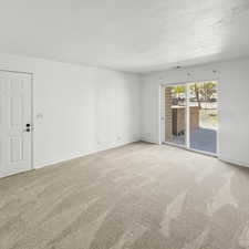 Empty living room with light carpet and baseboards