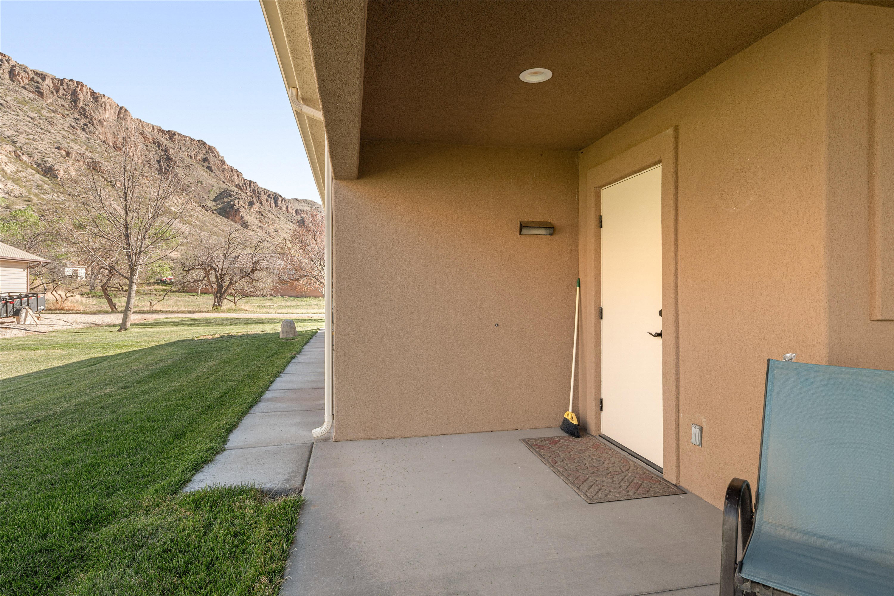 Entrance to property with a mountain view, a lawn, stucco siding, and a patio
