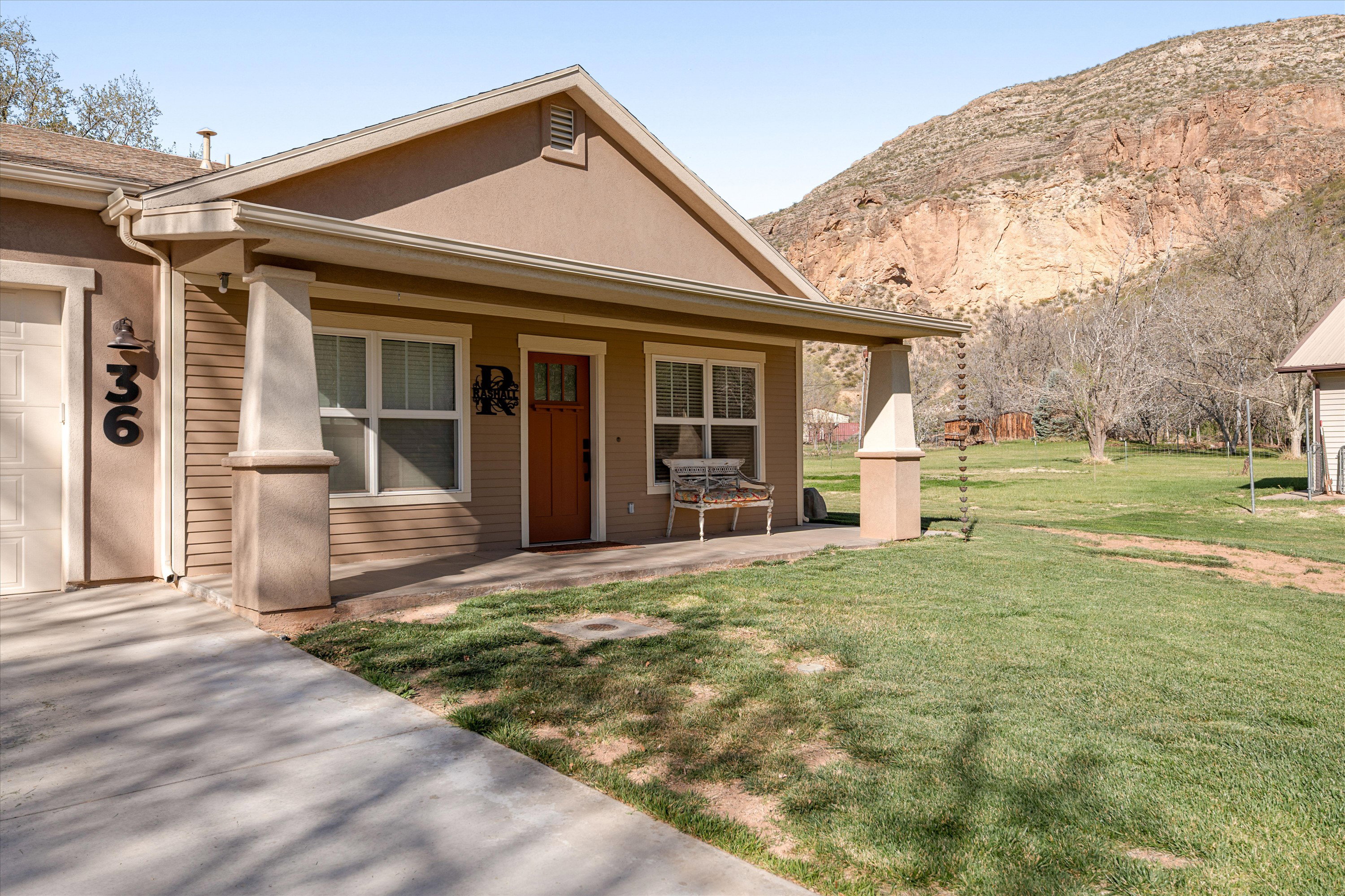 Bungalow-style home with a porch, stucco siding, a garage, a front lawn, and driveway