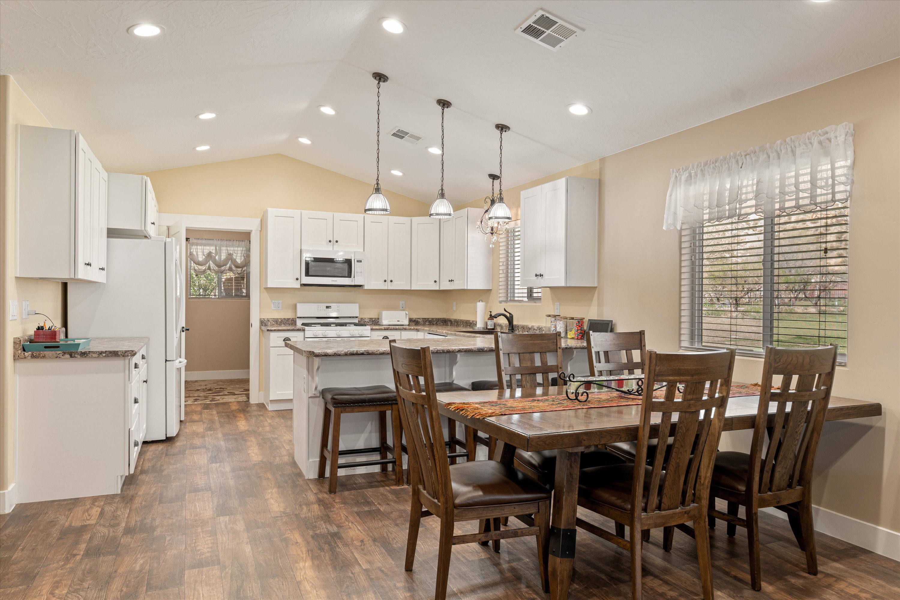 Dining area with dark wood-style floors, recessed lighting, and vaulted ceiling