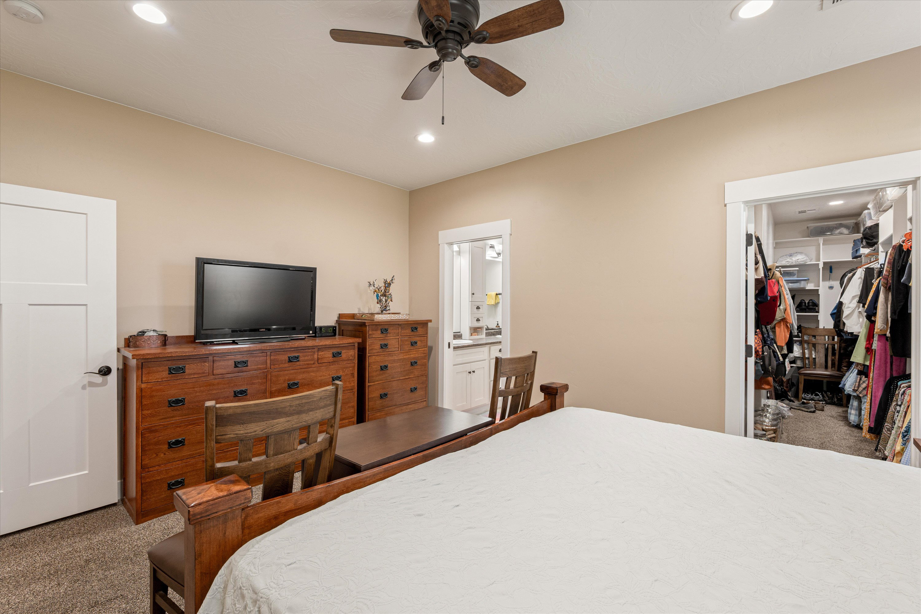Carpeted bedroom with a walk in closet, ceiling fan, recessed lighting, and ensuite bathroom