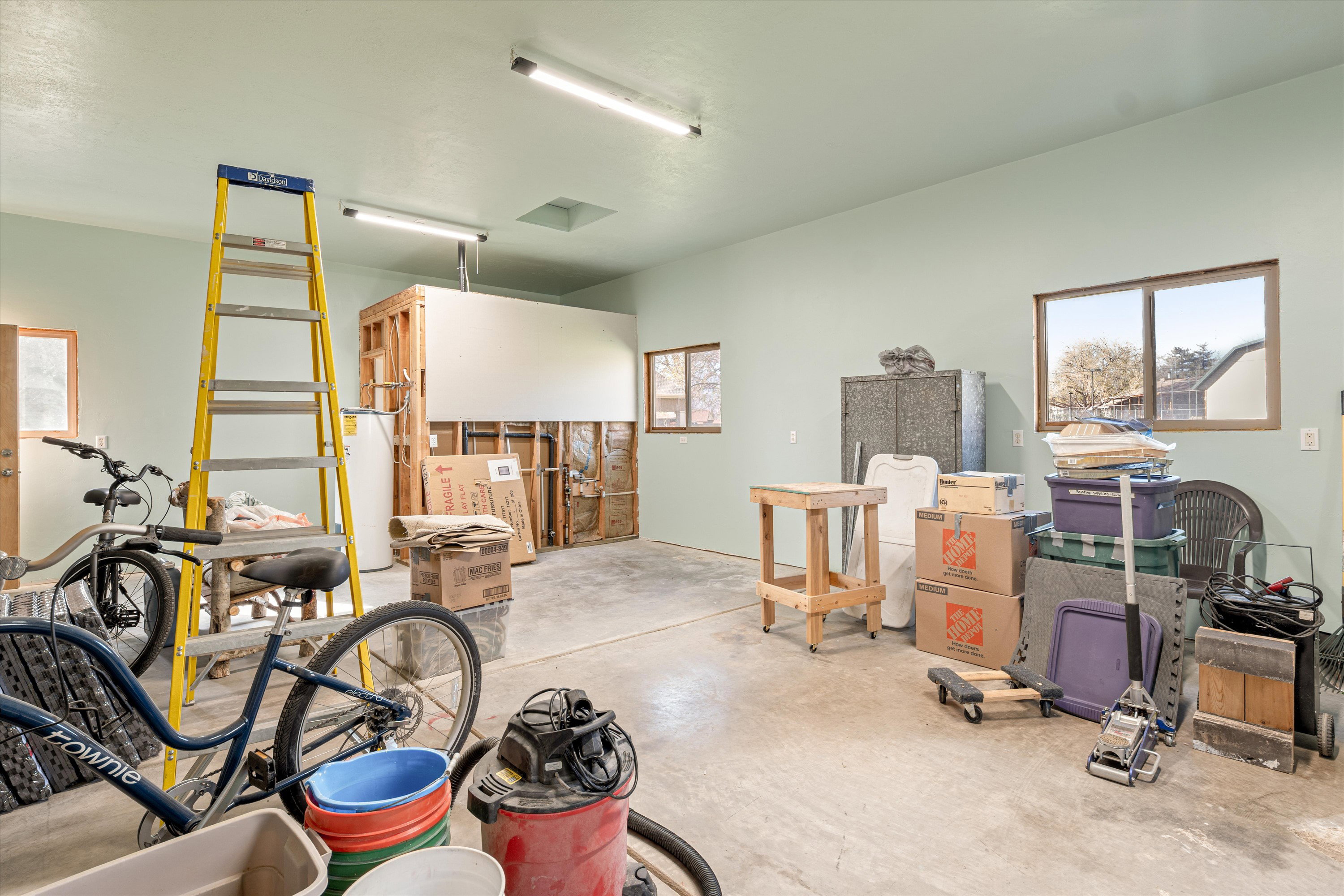 Misc room with concrete flooring, healthy amount of natural light, and water heater
