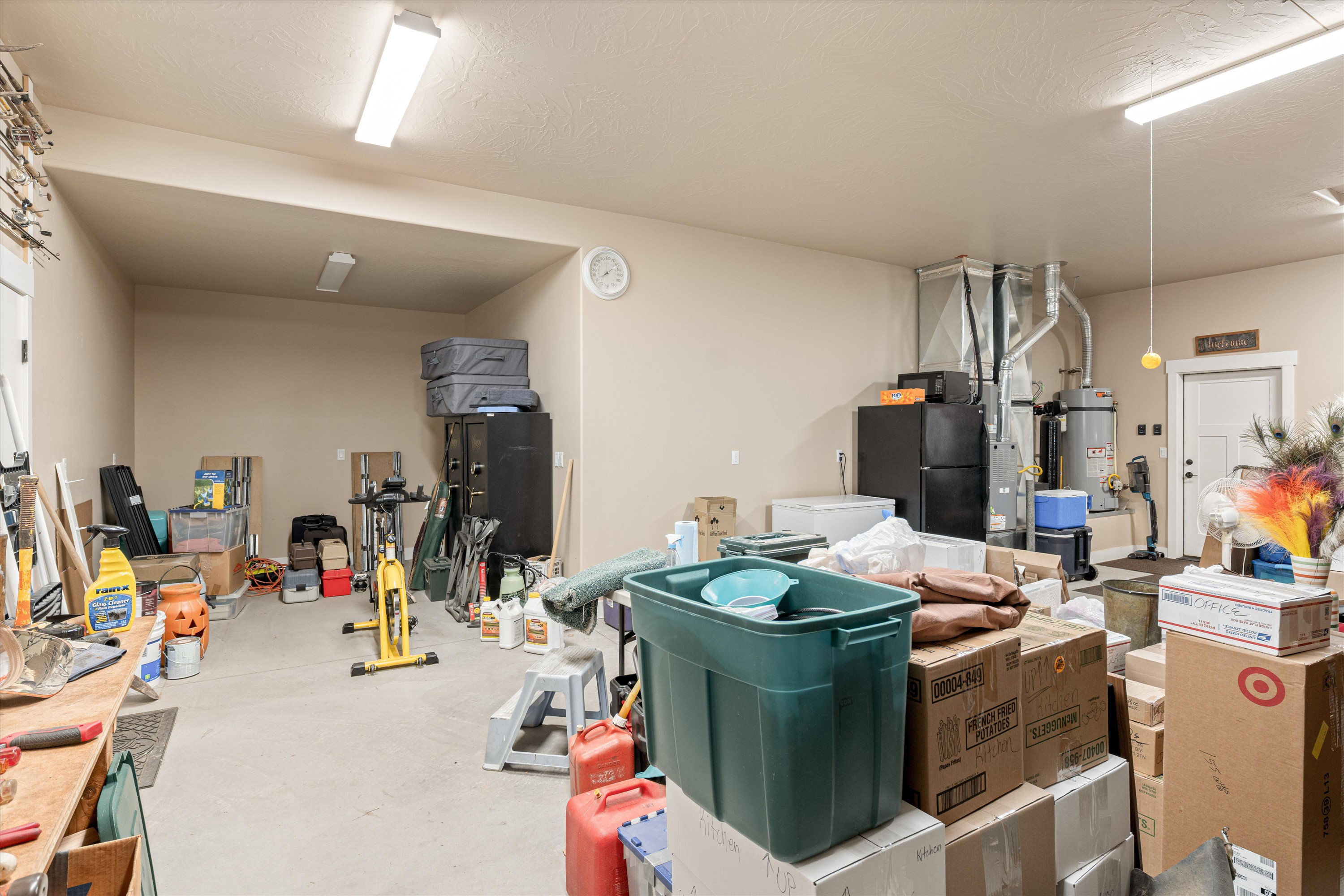 Garage featuring heating unit, freestanding refrigerator, gas water heater, and white fridge