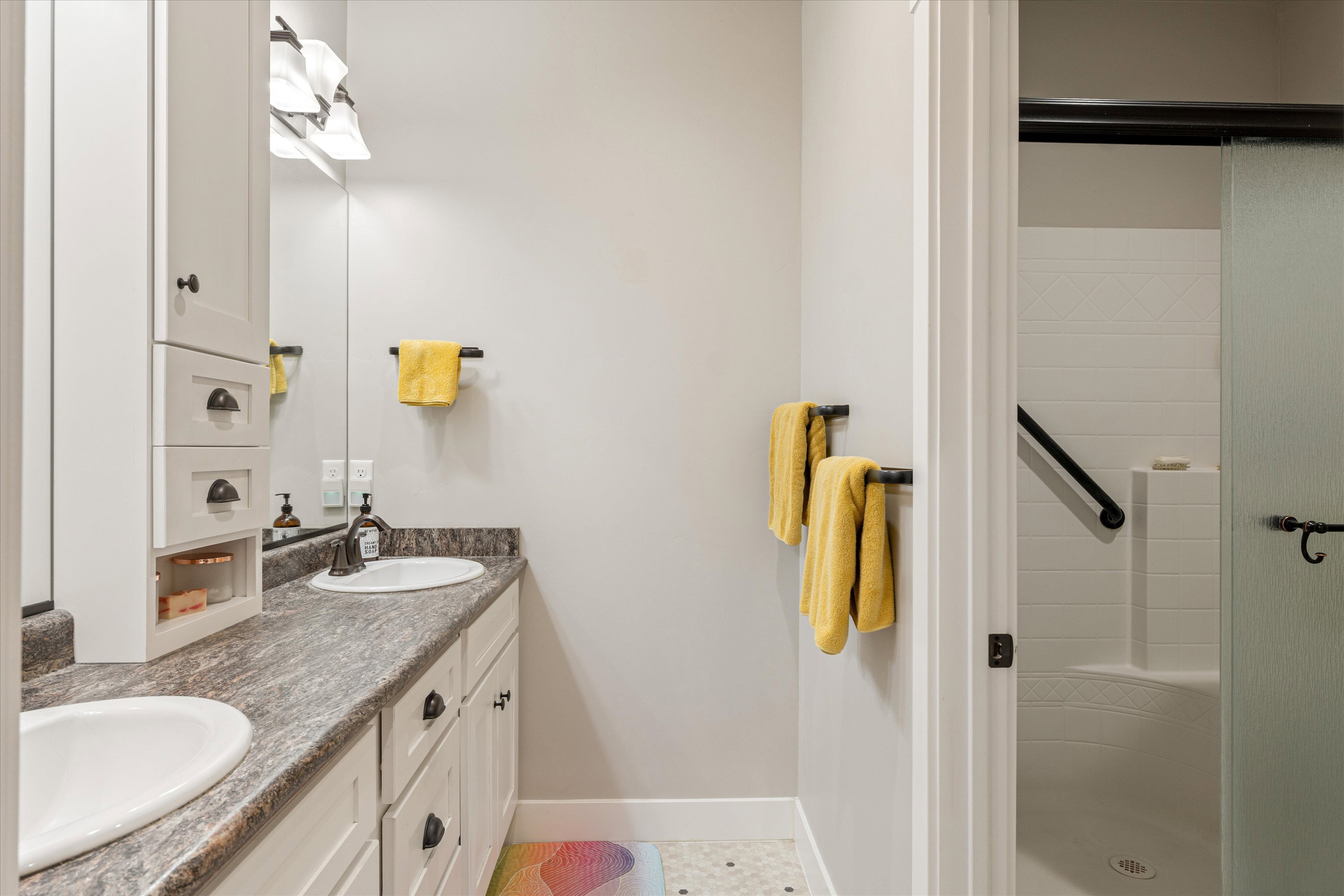 Full bathroom featuring double vanity, a shower stall, and light tile patterned floors
