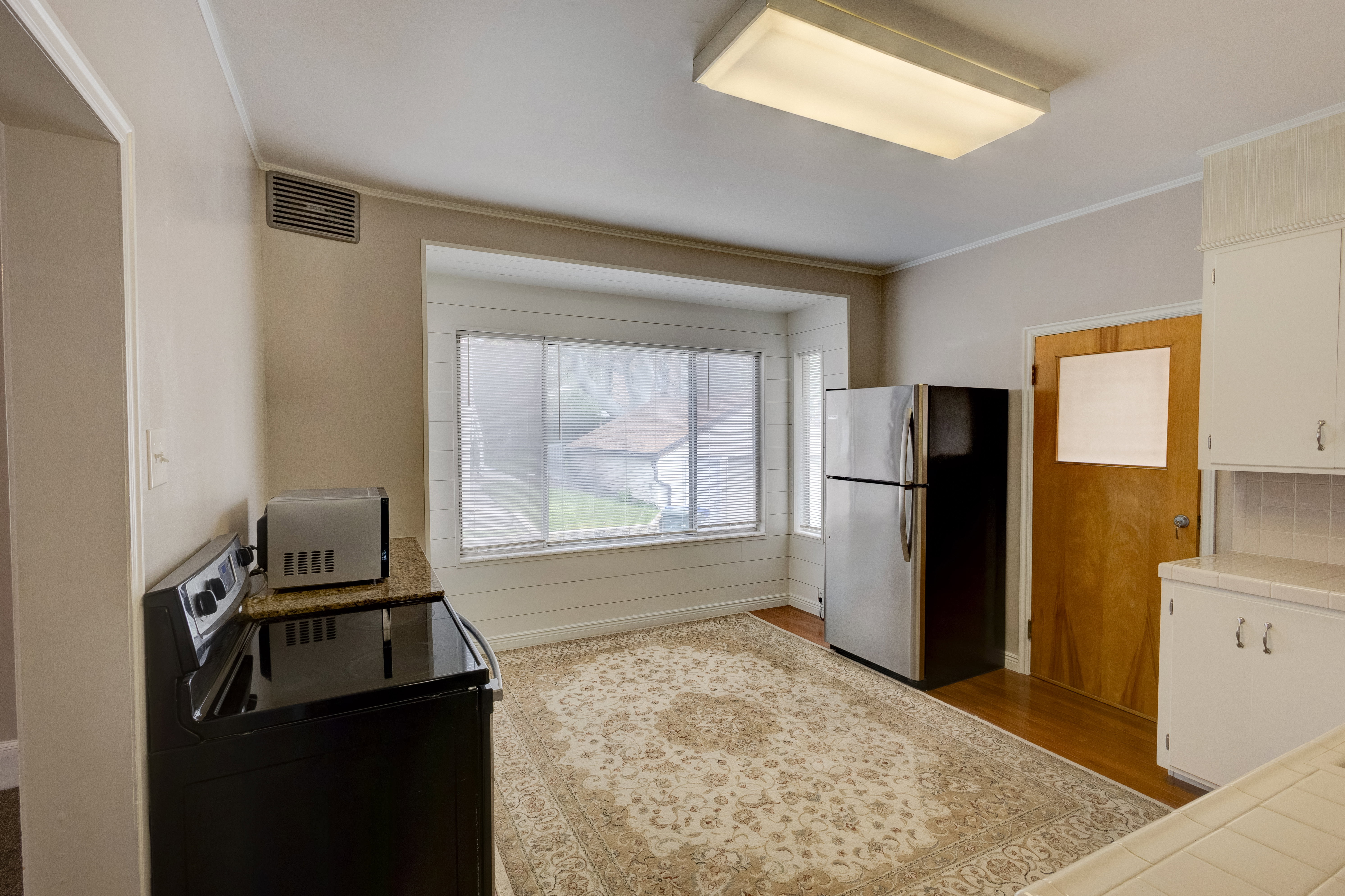 Kitchen with tile counters, black / electric stove, freestanding refrigerator, hardwood flooring, and ornamental molding