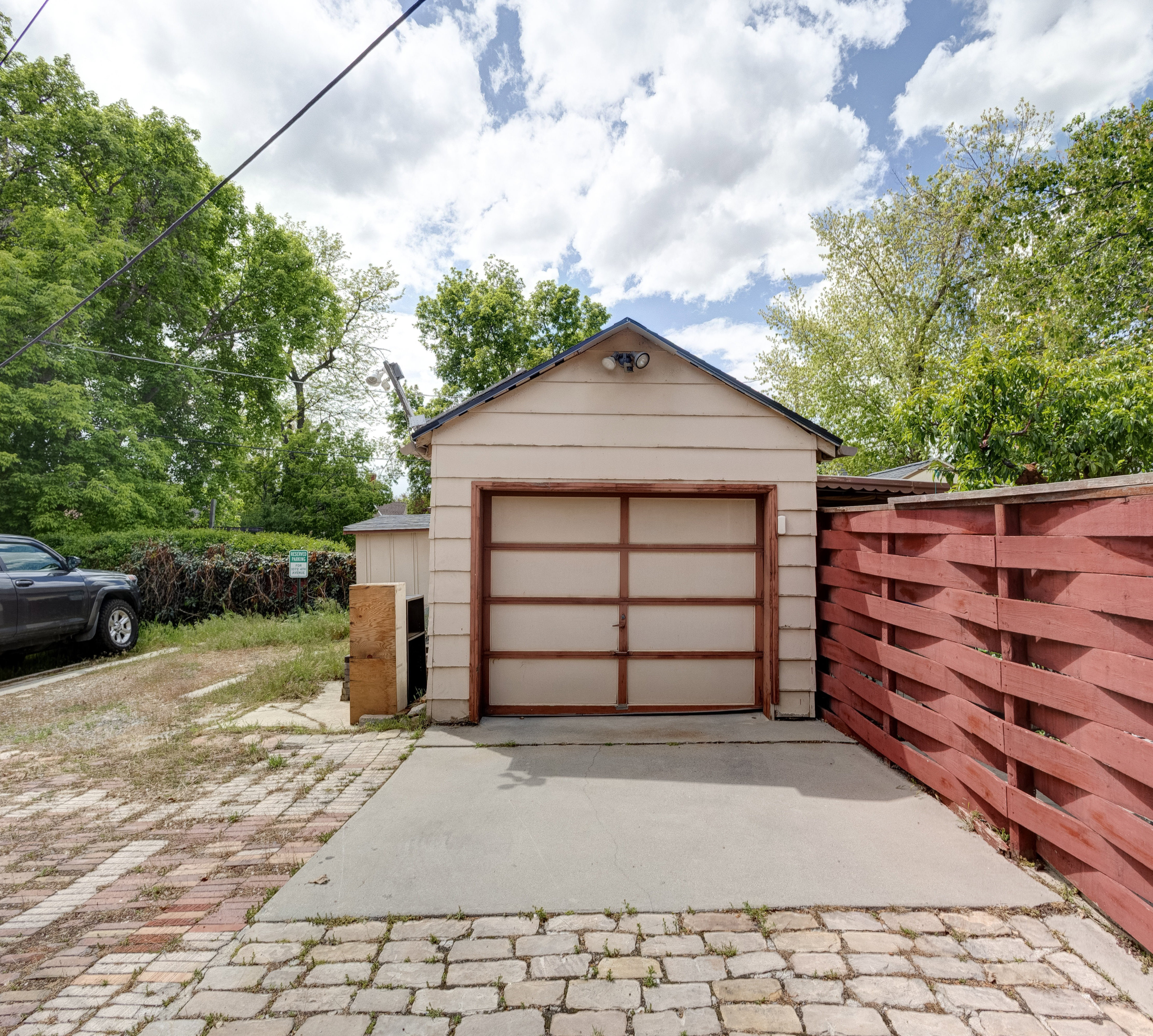 Detached garage featuring concrete driveway and extra parking space.