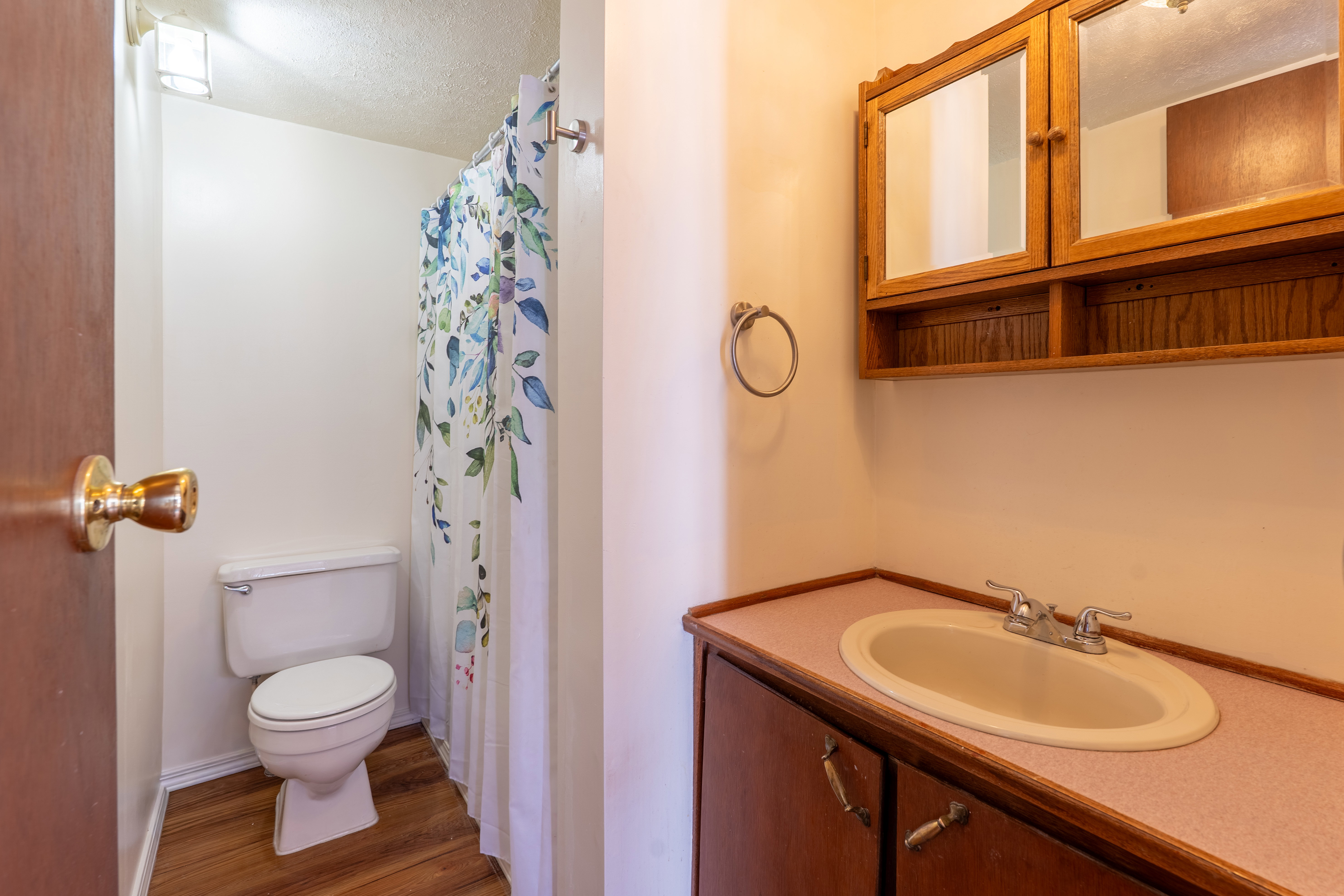 Full bathroom with a shower with shower curtain, vanity, wood finished floors, and a textured ceiling