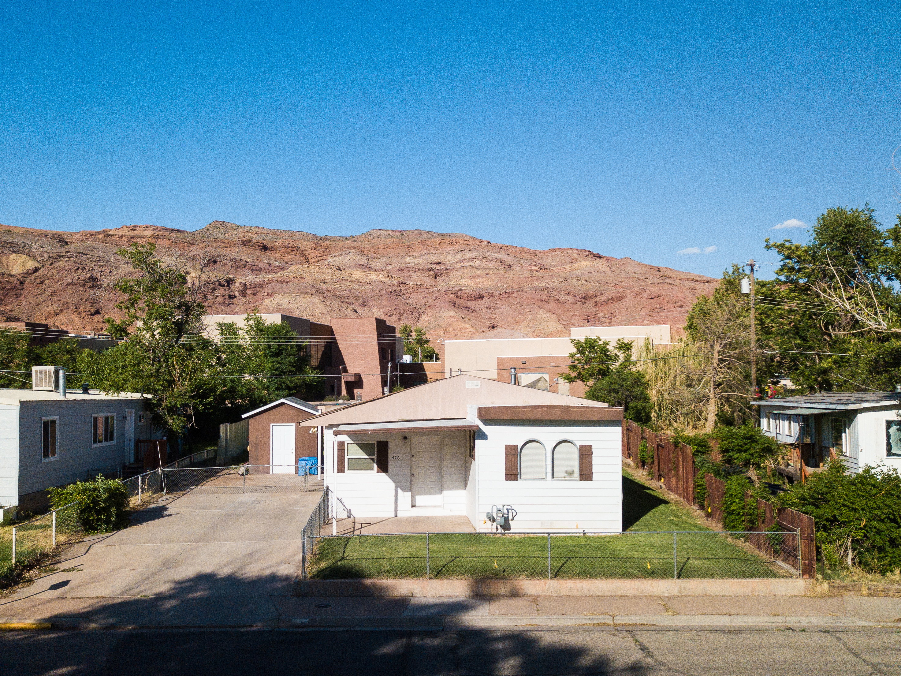 View of front of house with a mountain view, a fenced front yard, concrete driveway, and an outbuilding