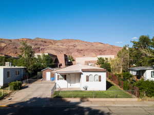 View of front of house with a mountain view, a fenced front yard, concrete driveway, and an outbuilding