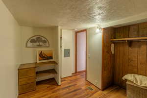Unfurnished bedroom with a textured ceiling, light wood finished floors, a closet, and electric panel