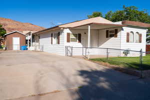 View of front facade featuring a gate, a mountain view, a fenced front yard, a shed, and concrete driveway