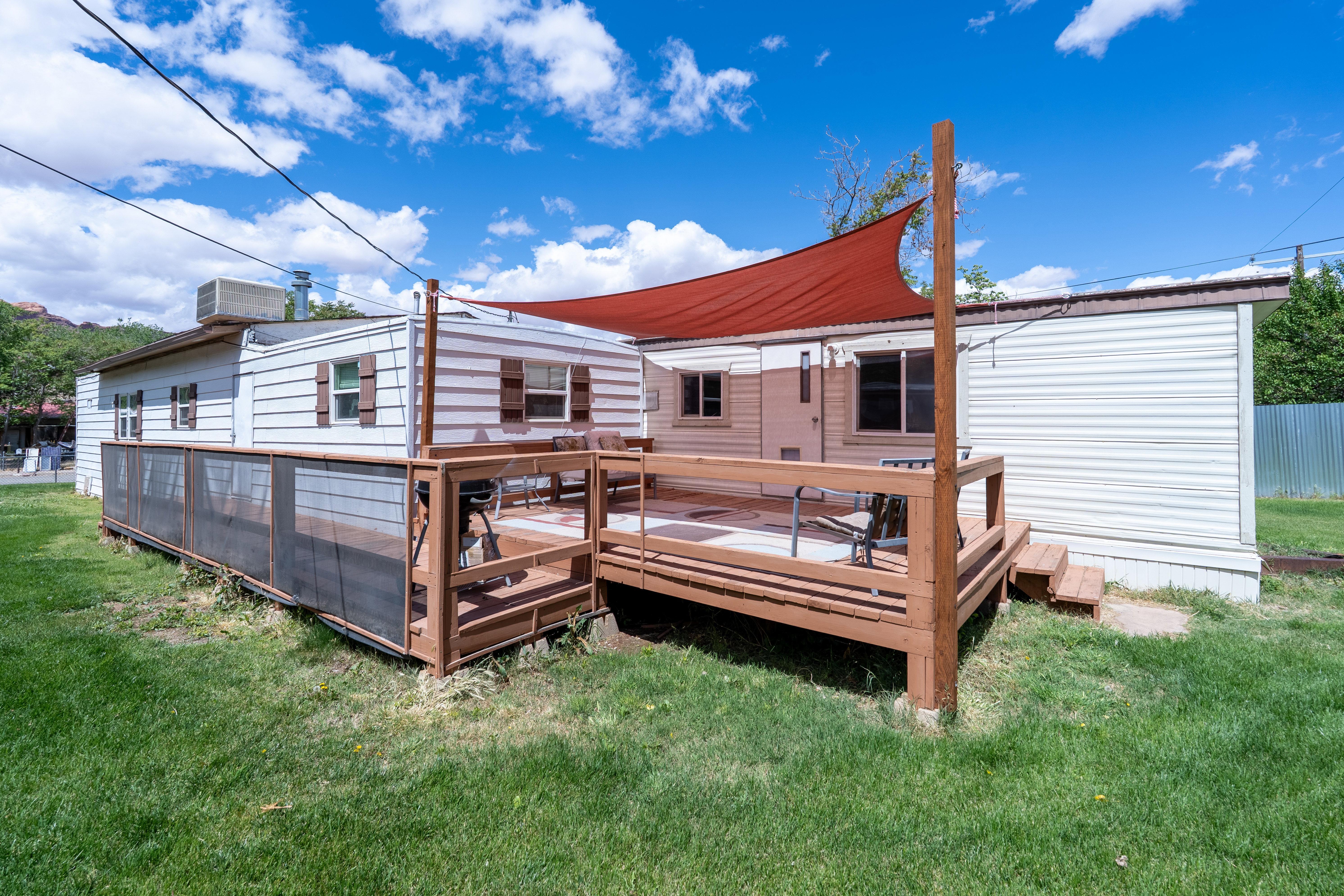 Rear view of house featuring a lawn and a deck