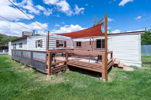 Rear view of house featuring a lawn and a deck