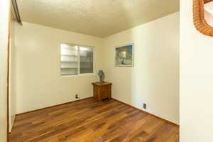 Empty room featuring a textured ceiling and wood finished floors