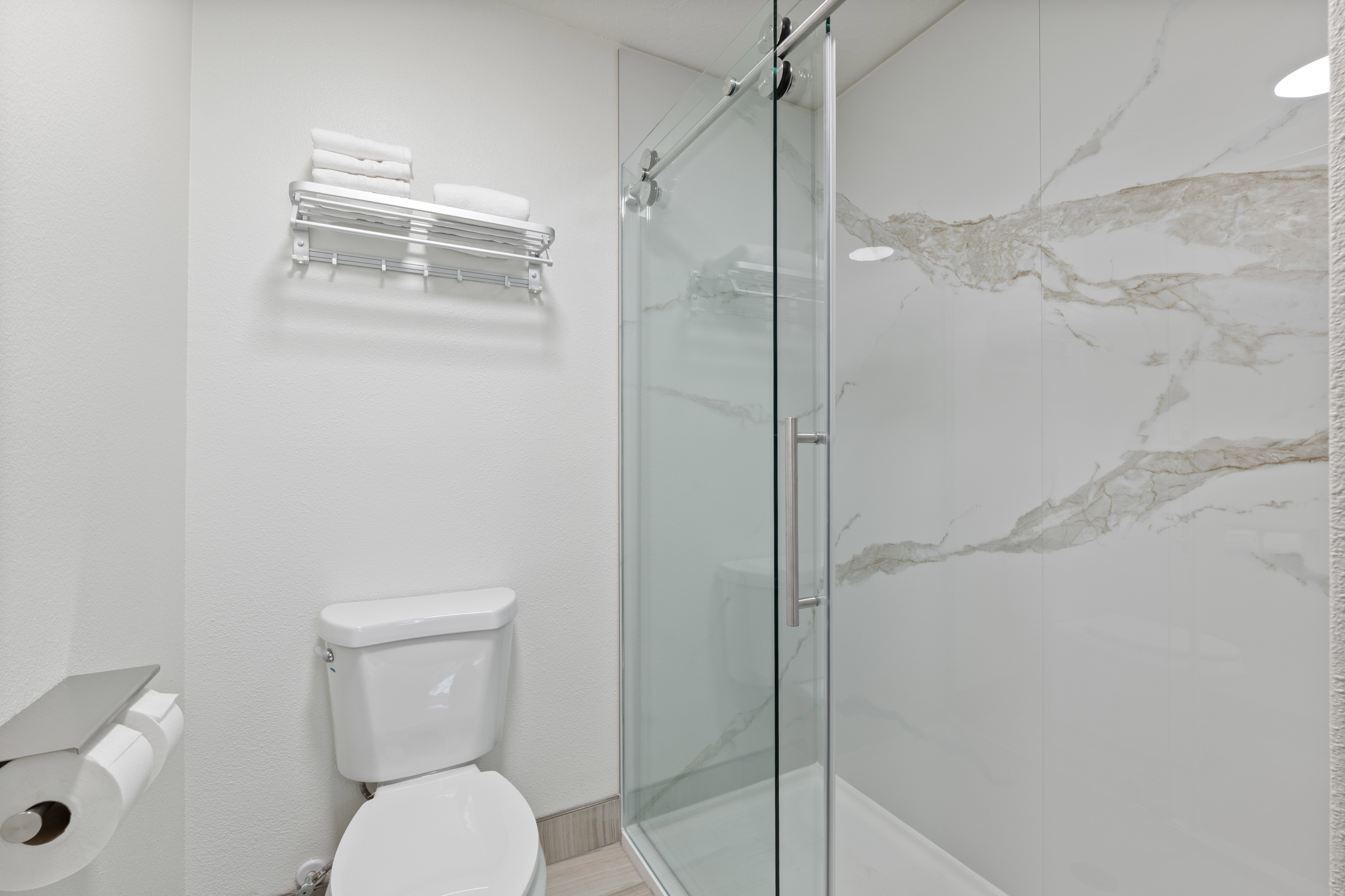 Full bath with toilet and a marble finish shower