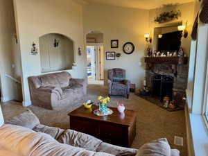 Living area featuring carpet flooring, arched walkways, a high ceiling, and a fireplace