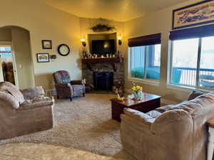 Living area with arched walkways, lofted ceiling, and a stone fireplace