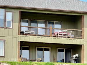 Back of property with a balcony off living room kitchen and patio off lower level family room