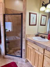Full bath with a separate shower, vanity, and light tile patterned floors