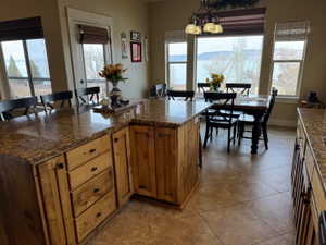 Kitchen with a kitchen bar, a kitchen island, dark stone counters, wood finish cabinetry, dining area