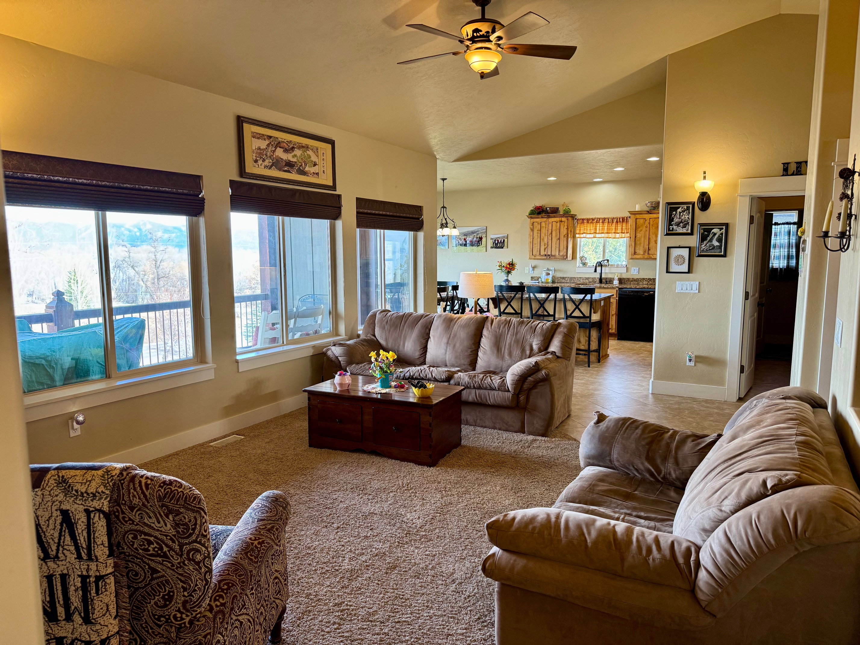 Living room featuring a ceiling fan, vaulted ceiling, large windows with lake view
