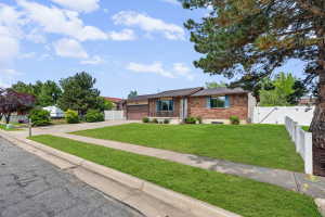 Ranch-style house with an attached garage, driveway, brick siding, and a gate