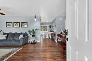 Living area featuring dark wood-style flooring and ceiling fan