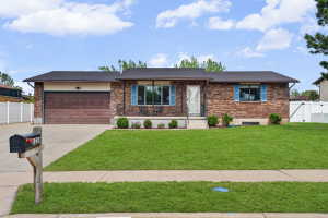 Ranch-style home featuring brick siding, an attached garage, driveway, and a gate