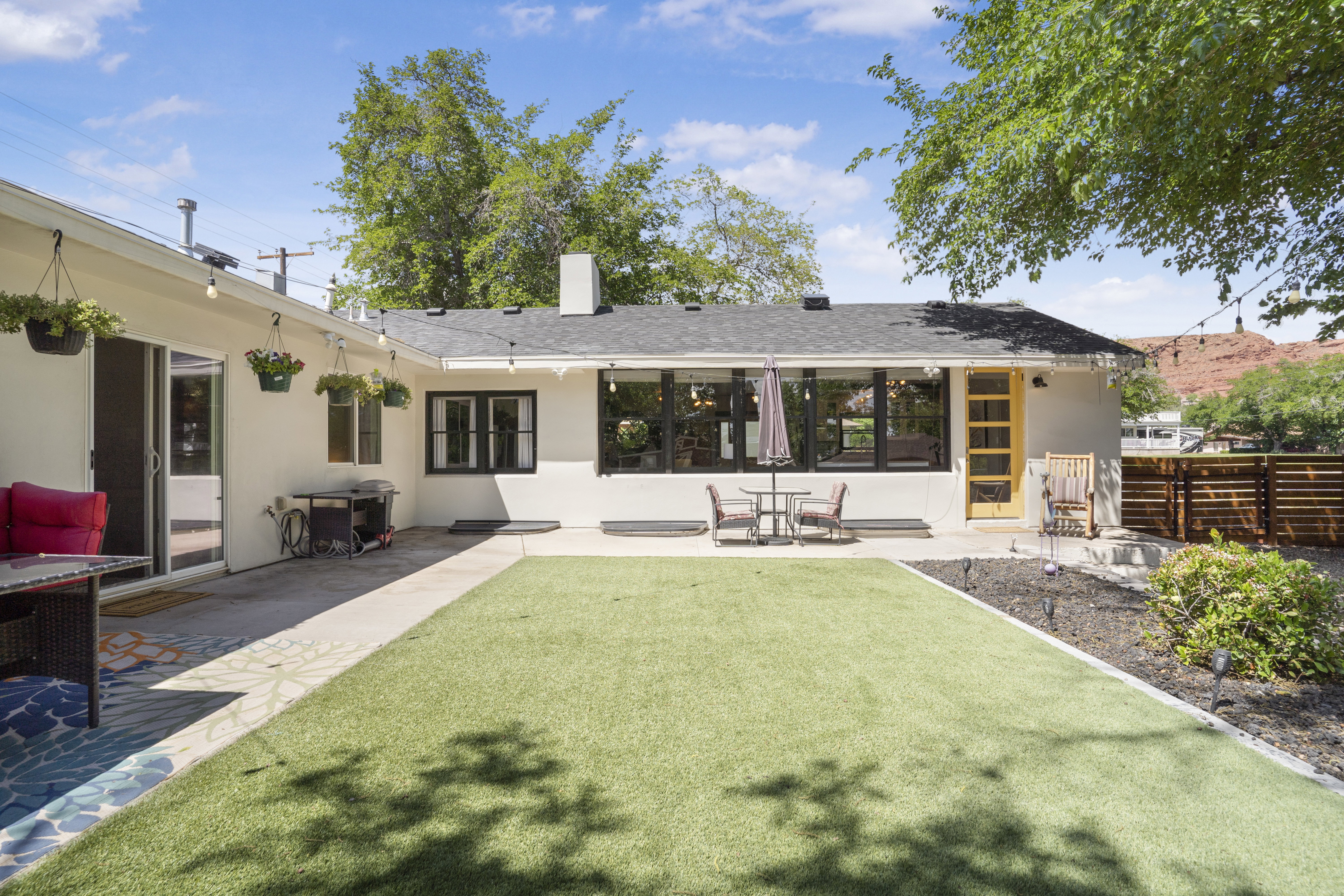 Rear view of house featuring a patio area, stucco siding, a chimney, and roof with shingles