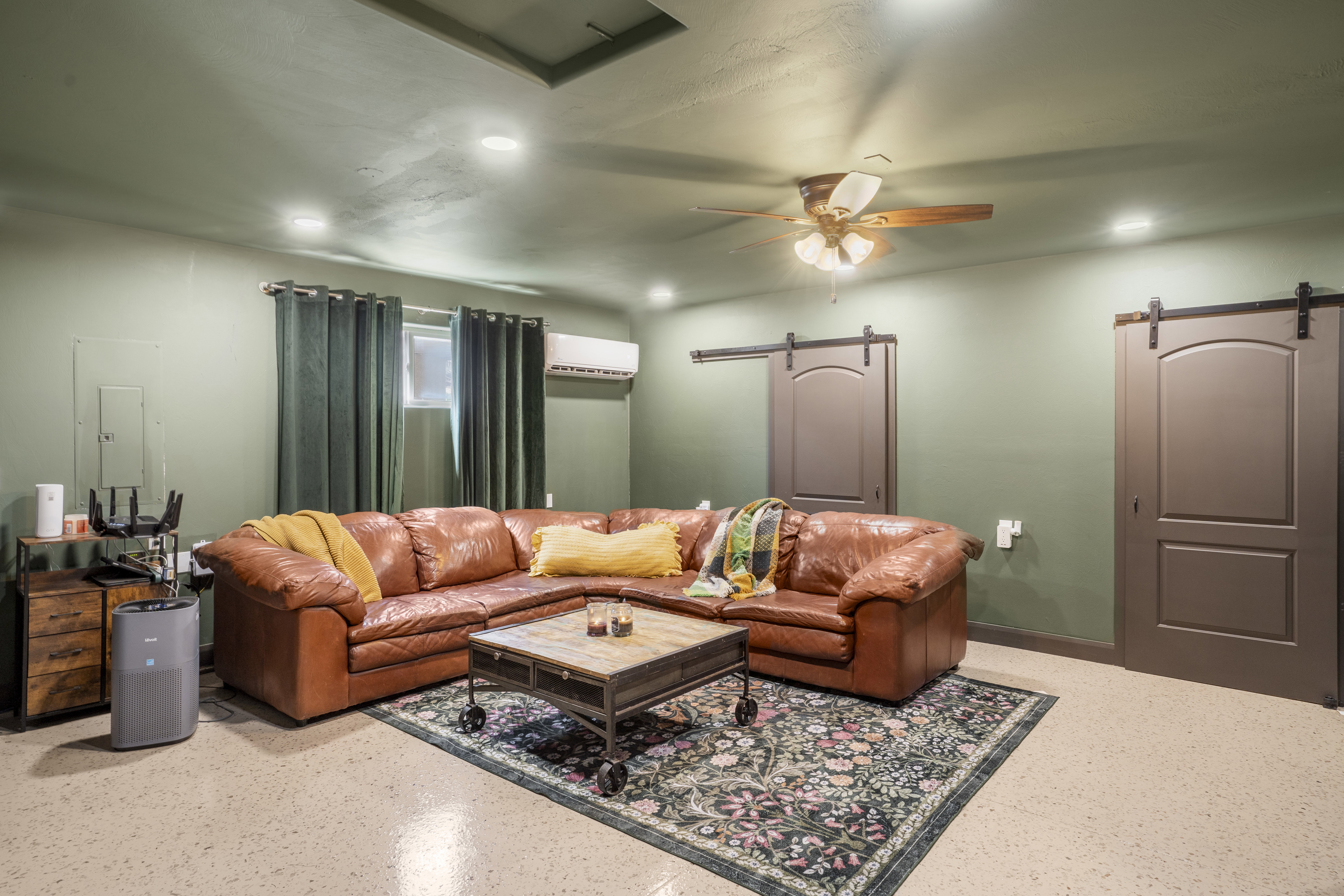 Living area with a barn door, ceiling fan, recessed lighting, and electric panel