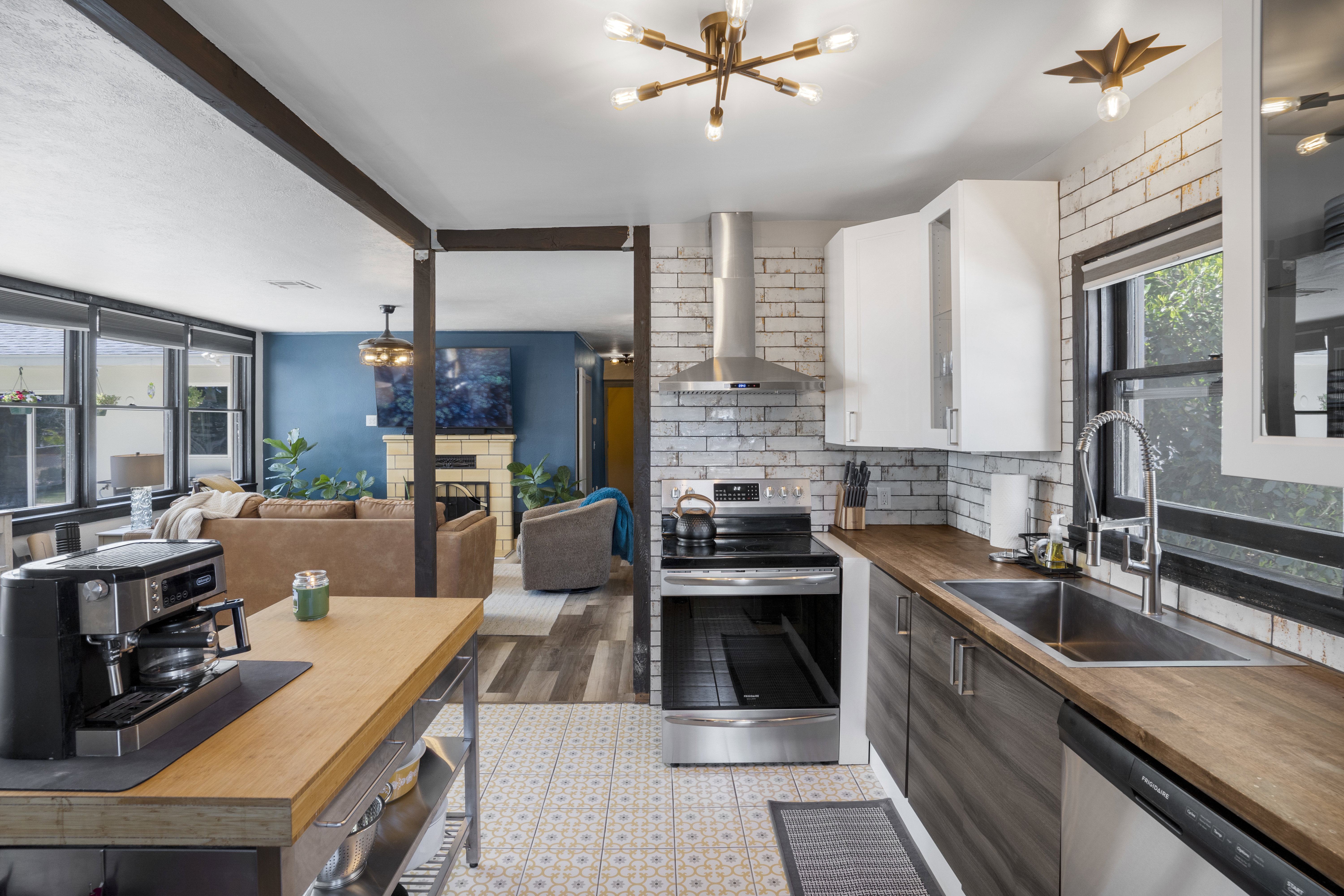 Kitchen featuring butcher block countertops, plenty of natural light, stainless steel appliances, open floor plan, and two tone cabinetry
