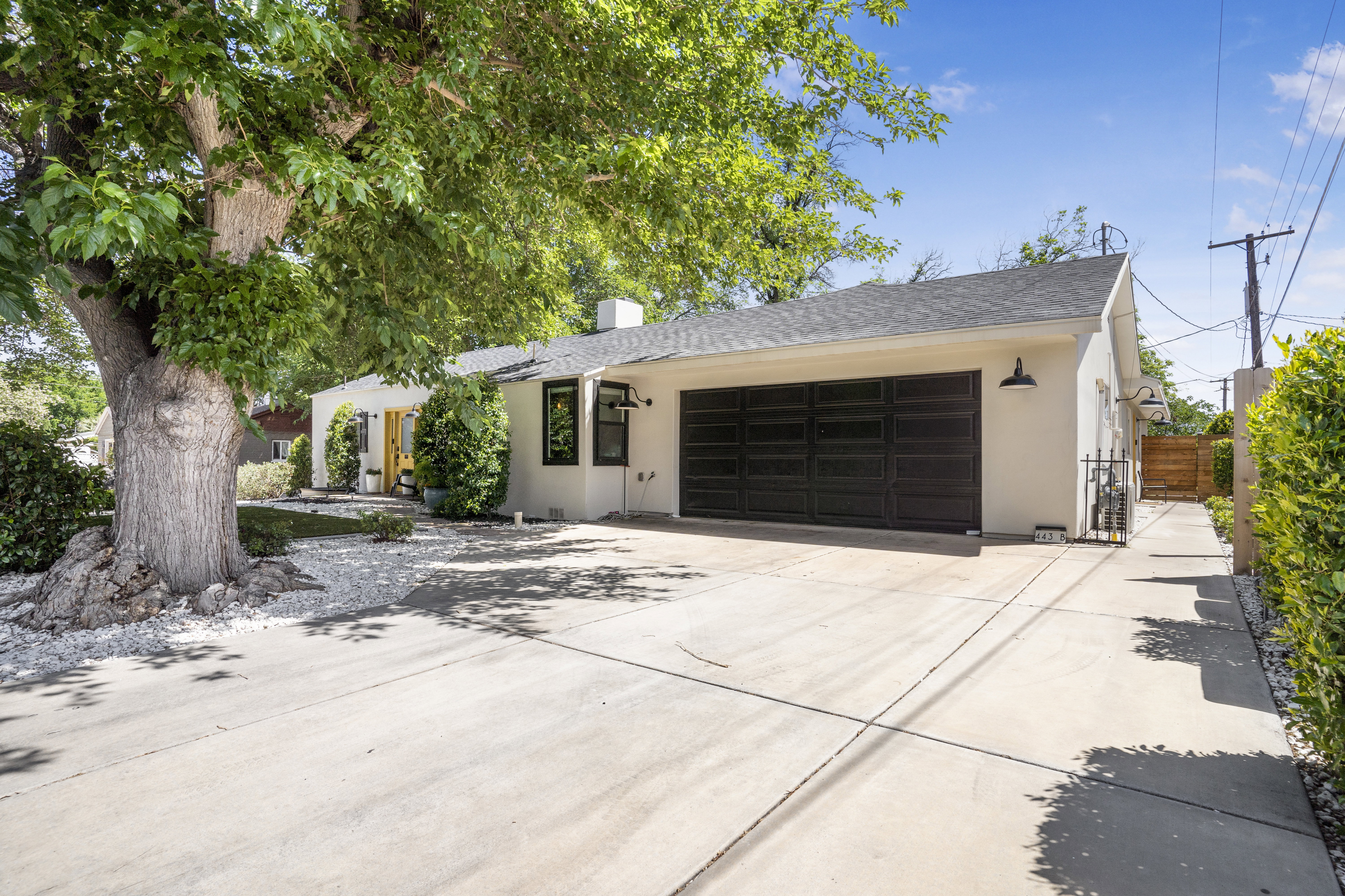 Single story home with an attached garage, stucco siding, driveway, a chimney, and a shingled roof