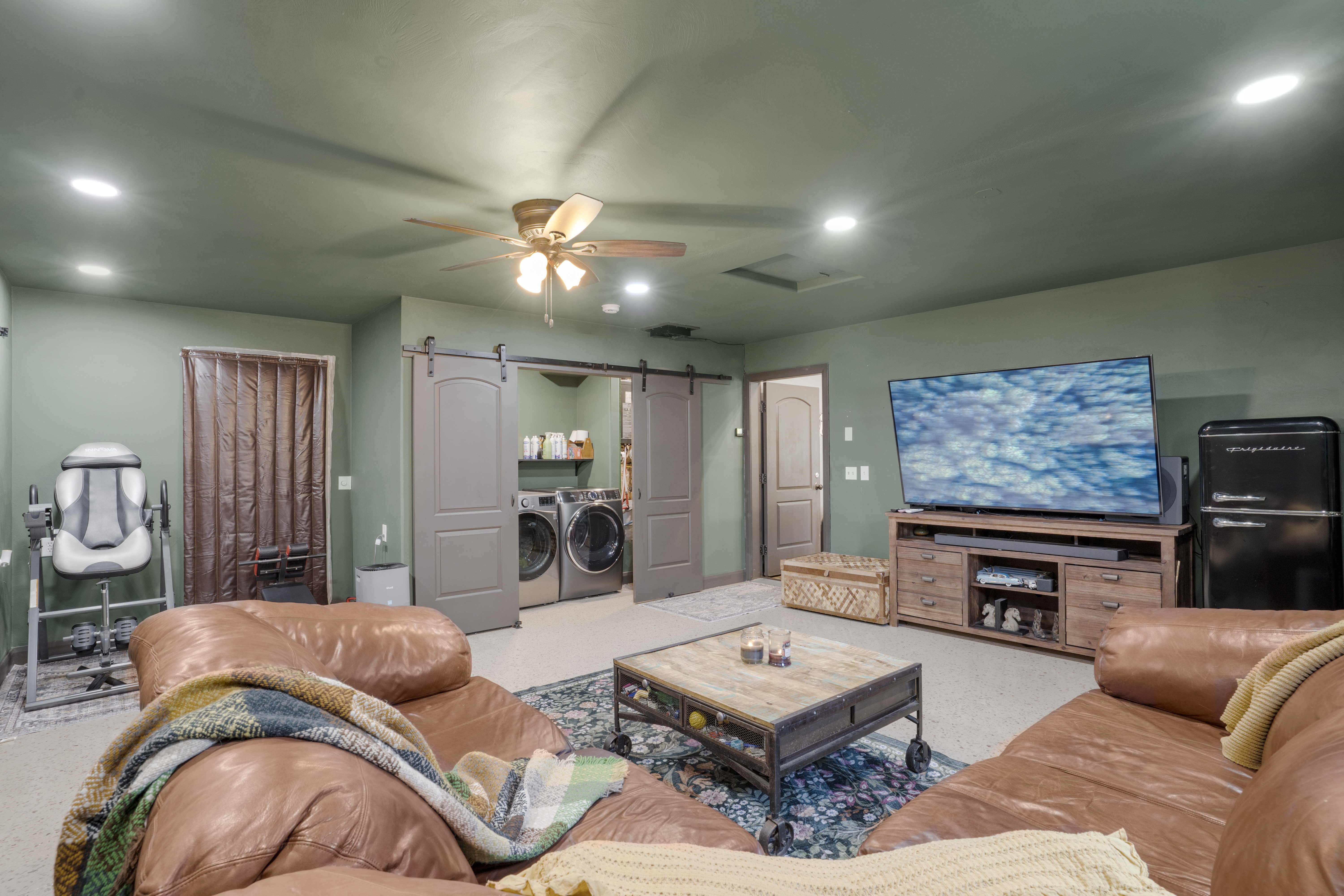 Living room with a barn door, washing machine and dryer, ceiling fan, and recessed lighting