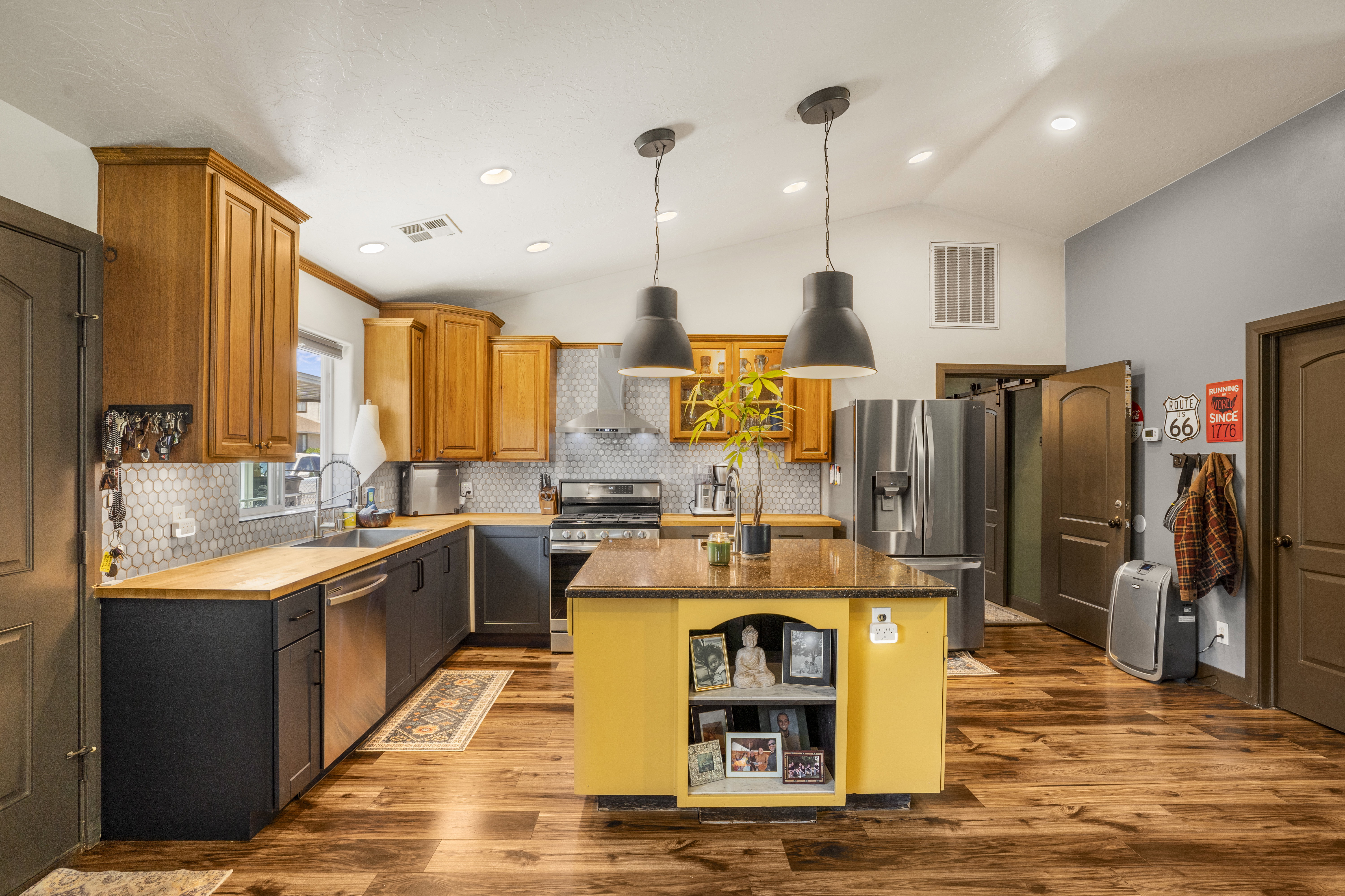 Kitchen with a center island, stainless steel appliances, open shelves, light wood finished floors, and lofted ceiling