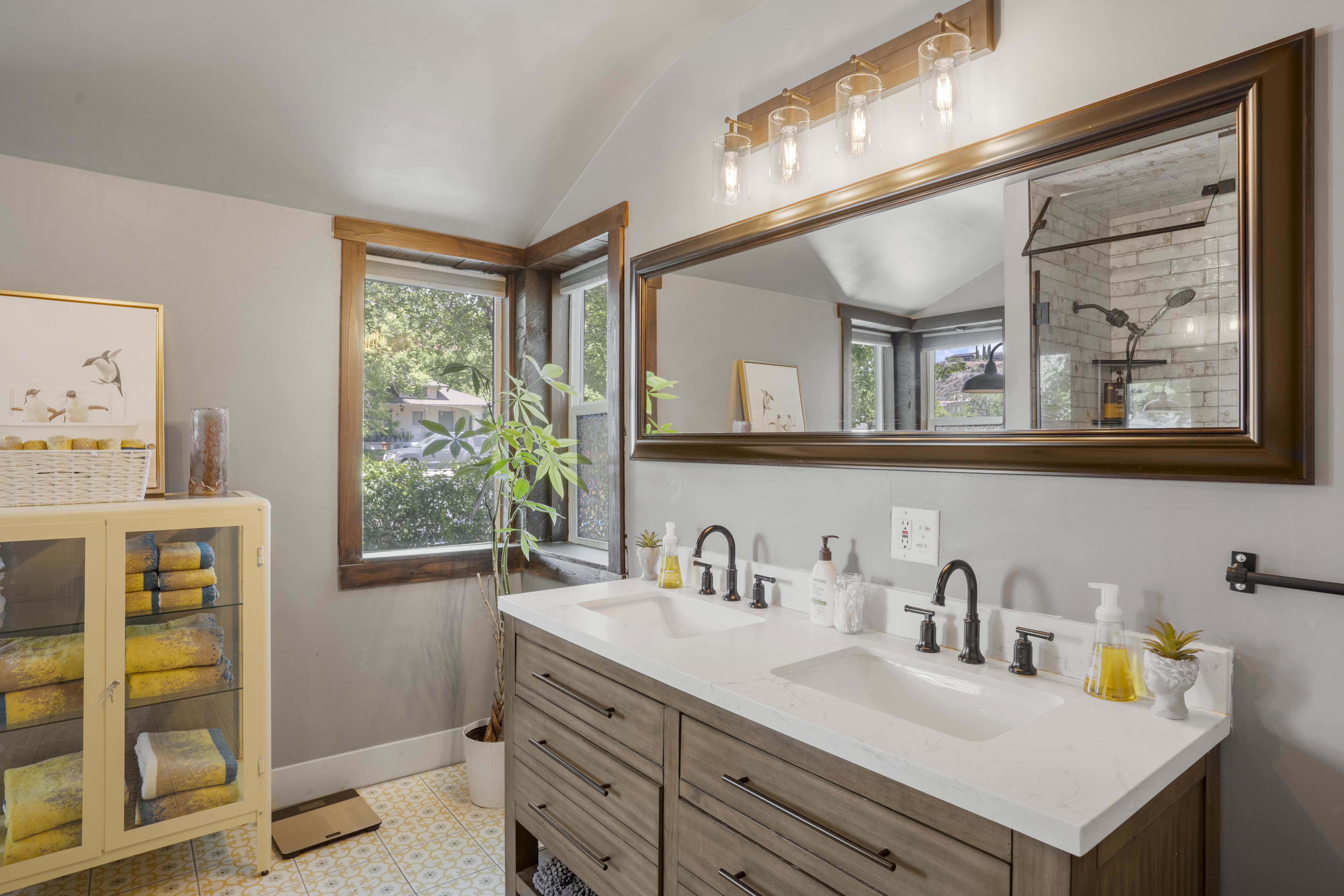 Full bathroom featuring double vanity, vaulted ceiling, and a tile shower