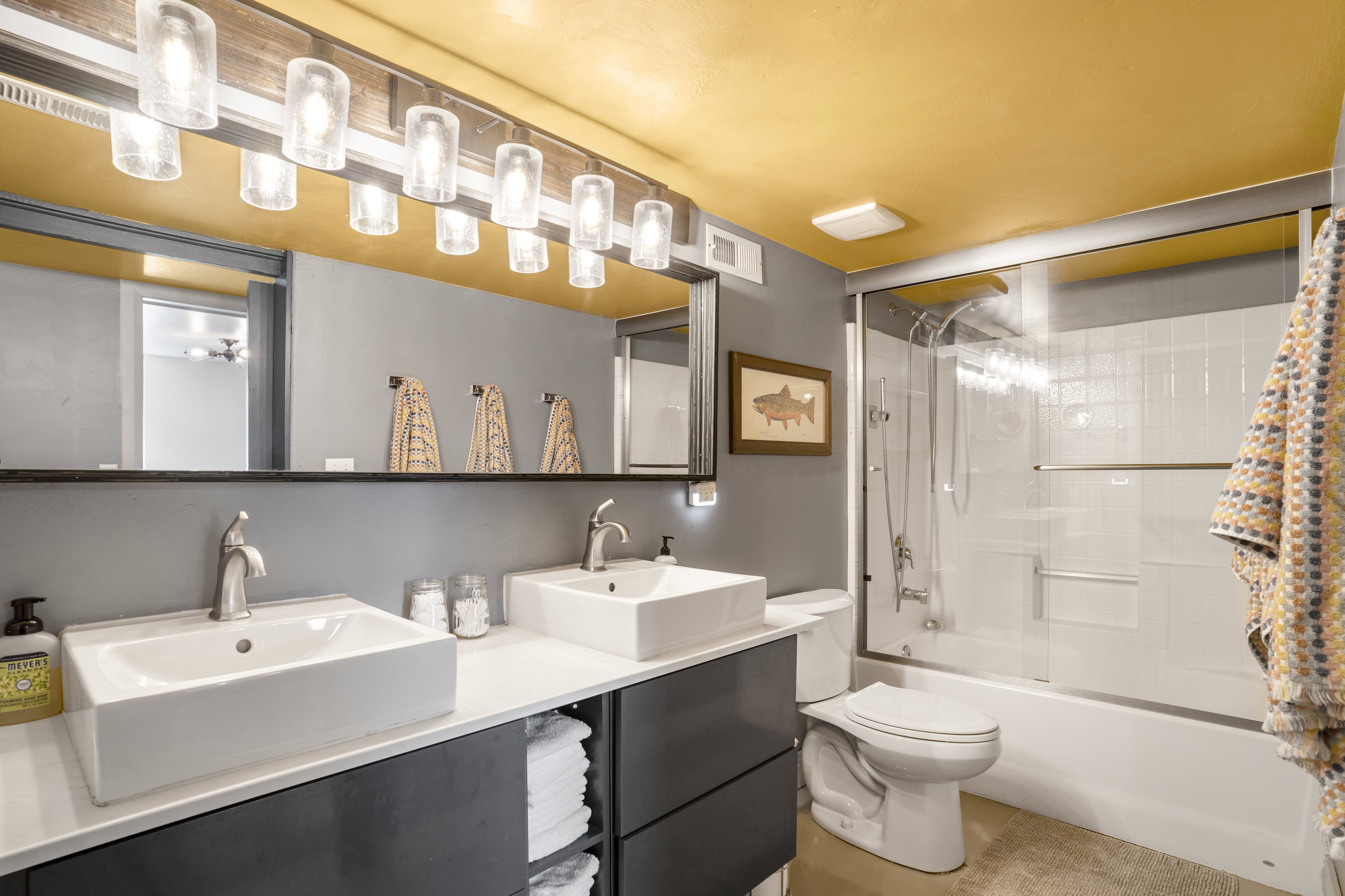 Full bathroom featuring double vanity and enclosed tub / shower combo