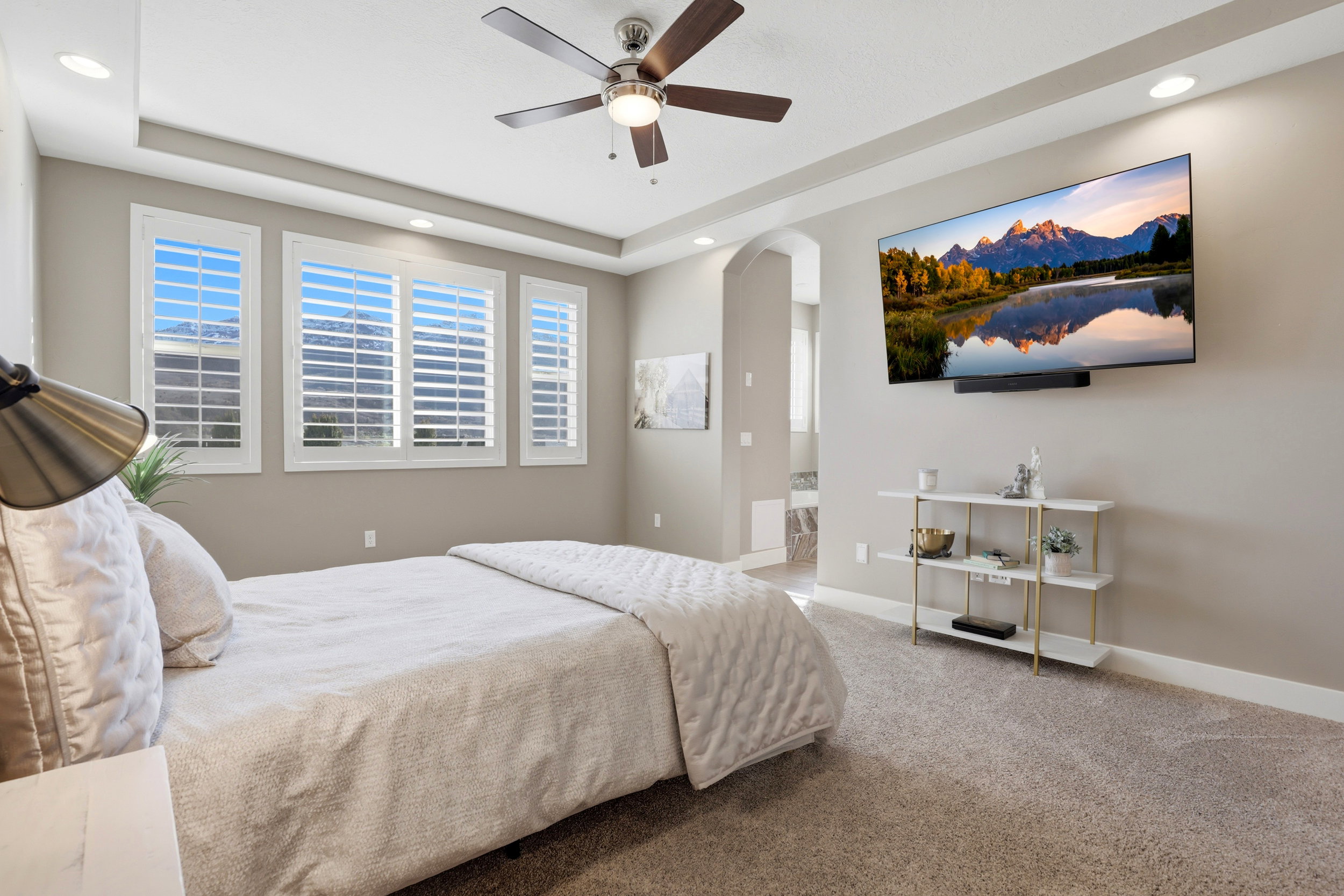 Bedroom with arched walkways, recessed lighting, light carpet, a ceiling fan, and ensuite bath