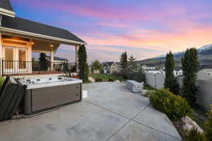 Fenced backyard with a hot tub, a patio area, a shed, and a residential view