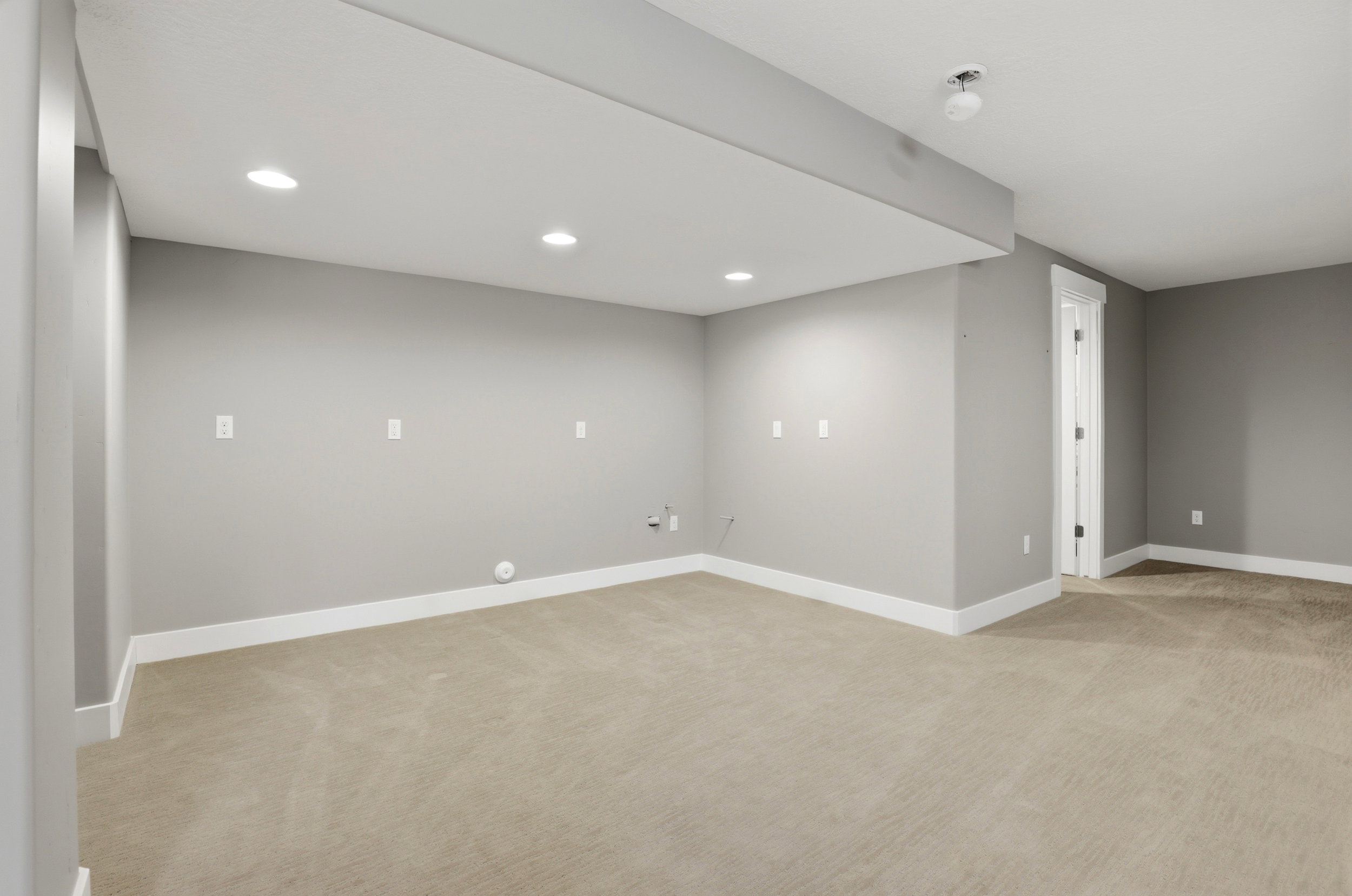 Empty room with light colored carpet and recessed lighting